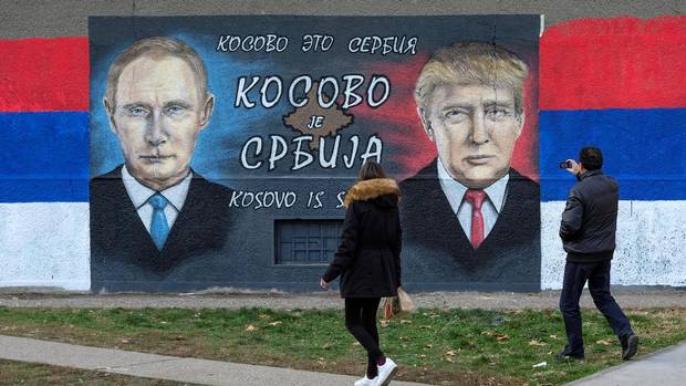 A man takes pictures of a mural of Russian President Vladimir Putin and U.S. President Donald Trump in Belgrade in December.