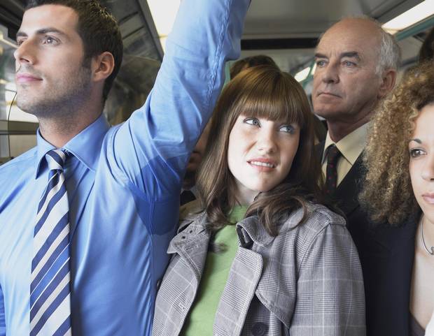 Closeup of a female commuter standing by man's wet armpit in a crowded train