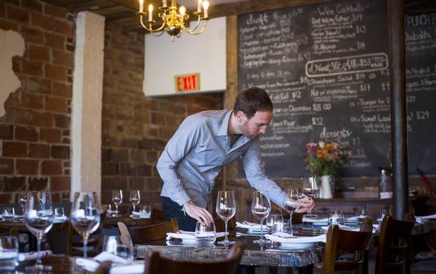 A server preps tables before opening.