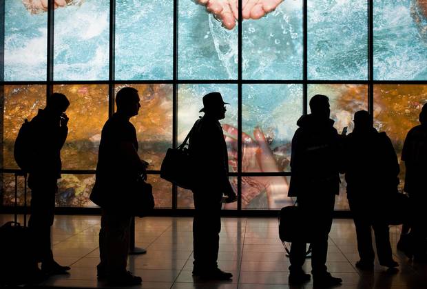 The silhouettes of travelers are seen standing in line at the Fort McMurray Airport.