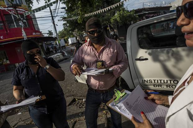 Investigators process the crime scene of a man shot to death in downtown San Salvador, El Salvador, May 29, 2015.