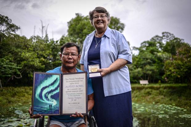 Tun Channareth, left, and Sister Denise Coghlan, from the International Campaign to Ban Landmines, stand in front of a crater made by a bomb dropped over Cambodia during its wartime years. Mr. Channareth, whose legs were severed by a landmine in 1982, travelled to Oslo in 1997 to receive the Nobel Peace Prize on behalf of the ICBL for its advocacy against landmines.