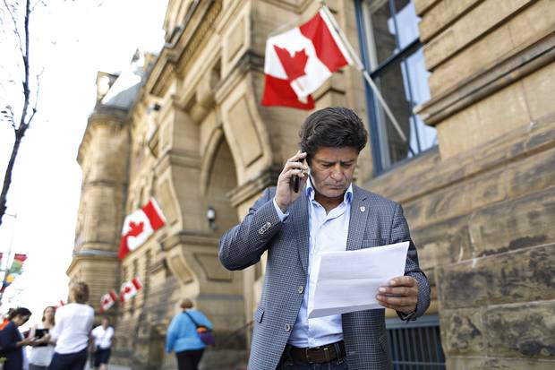 Jerry Dias reads a copy of an article given to him from a member of the PMO outside Langevin Block.