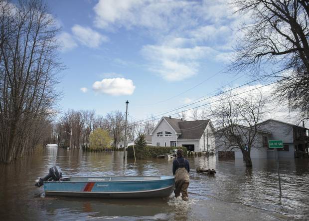 Patrice Pepin walks with his boat down Fournier Street in the flood zone along the Ottawa River in of Saint-André-d'Argenteuil, Que., in May, 2017.