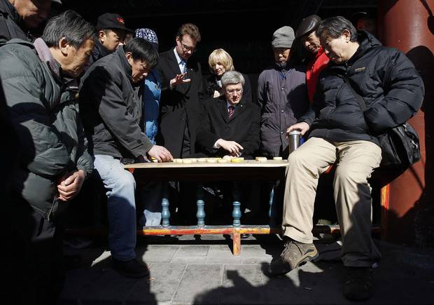 Mark Rowswell, centre left, is seen with then prime minister Stephen Harper and his wife Laureen, as they watch a game of chess while touring the Temple of Heaven in Beijing in 2012.