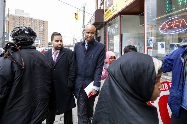 Mr. Hussen weaves his way through a crowd with Zubair Patel, his director of operations and outreach.