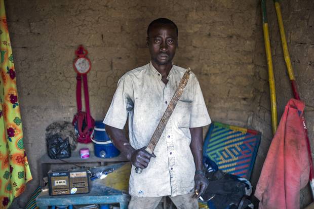 A Malian man poses at his home with a machete to protect himself from Islamist rebel groups, in Mopti, in 2013.