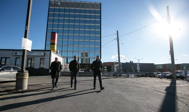 Mr. Gibson, left, Mr. Beattie and Mr. Barclay stroll through the parking lot where their new office complex is going up in downtown Kitchener The King Street West location is only a few feet from Kitchener’s soon-to-open LRT line.