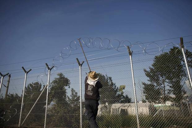 A worker places barbed wire on a fence at the Greek-Macedonian border.