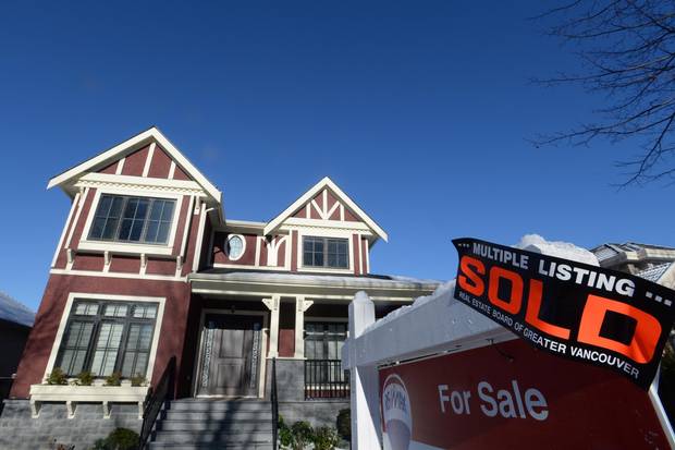 A real estate sold sign is shown outside a house in Vancouver.