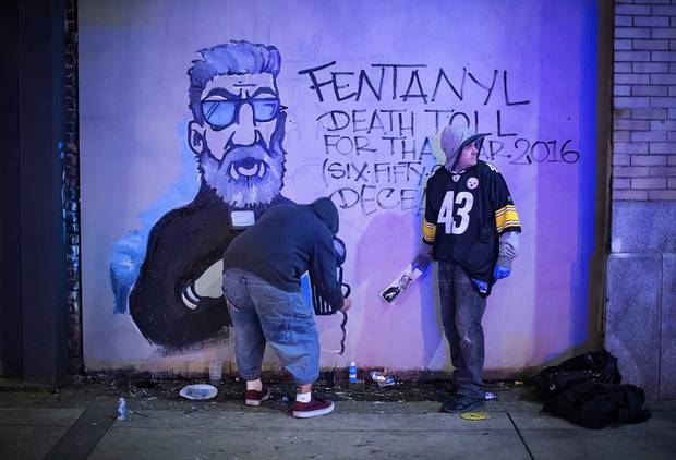 Artist Smokey D, left, paints an anti-Fentanyl art piece while his friend, Danny, keeps watch for police.