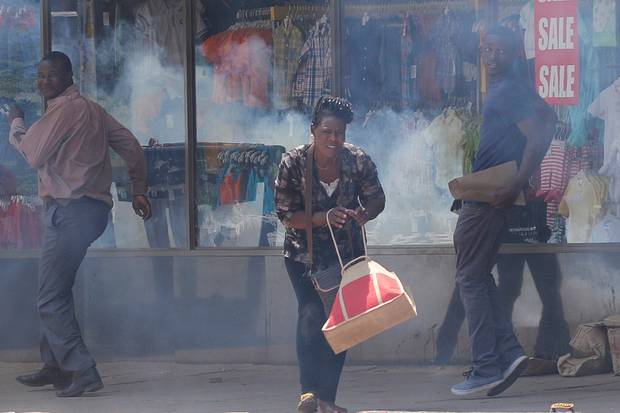 People flee tear gas during clashes between police and street vendors in central Harare on Sept. 27, 2016.