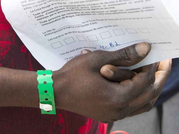 Aa asylum seeker holds on to his paperwork as he leaves Olympic Stadium.