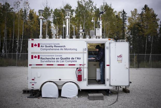 Ryan Abel of the Wood Buffalo Environmental Association checks data at an Environment Canada air quality monitoring station in Fort McKay, Alta., in September 2014.