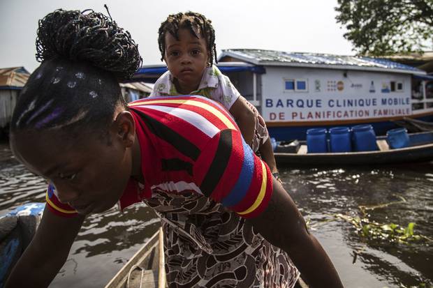 Flavienne San and her daughter Ana head home from contraception boat, nicknamed the Barque Mobile, in So-Ava, Benin. The boat and its crew travel from village to village in a lagoon in southern Benin to spread information about family planning.
