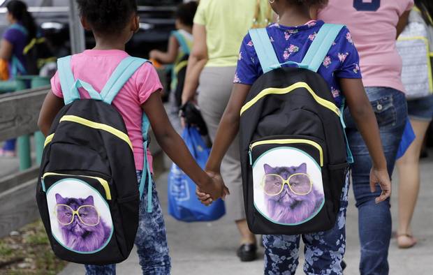 Students hold hands as they walk to school with their new book bags in Miami.