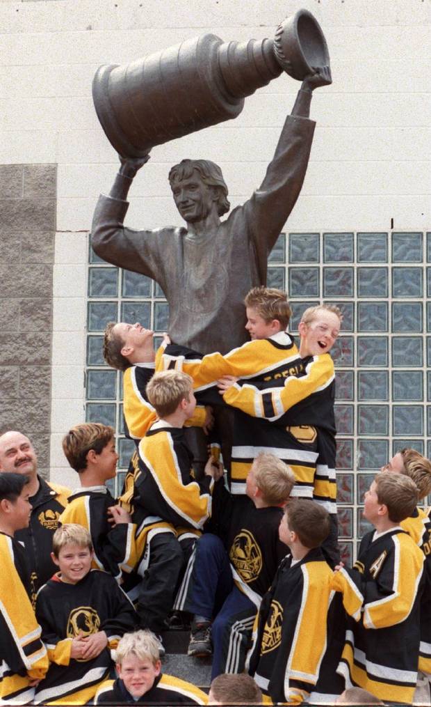 Members of the Northwest Zone Hawks atom hockey team climb onto the Wayne Gretzky statue outside the Skyreach Centre in Edmonton, Saturday, Apr.17, 1999. There has been a steady flow of fans to the statue since Gretzky announced his retirement Friday in New York.