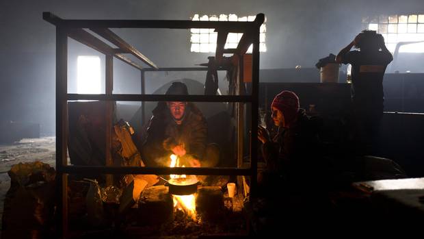 An Afghan refugee boils water on a fire to make tea in an abandoned warehouse where he and other migrants took refuge in Belgrade, Serbia.