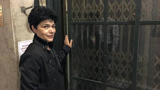 Elevator operator Anna Carroca begins to open the door to a 108-year-old manually controlled elevator at 10 Adelaide Street East in Toronto.