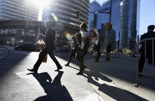 Pedestrians cross Lakeshore Boulevard W. at York Street during an afternoon rush hour in May 2016.