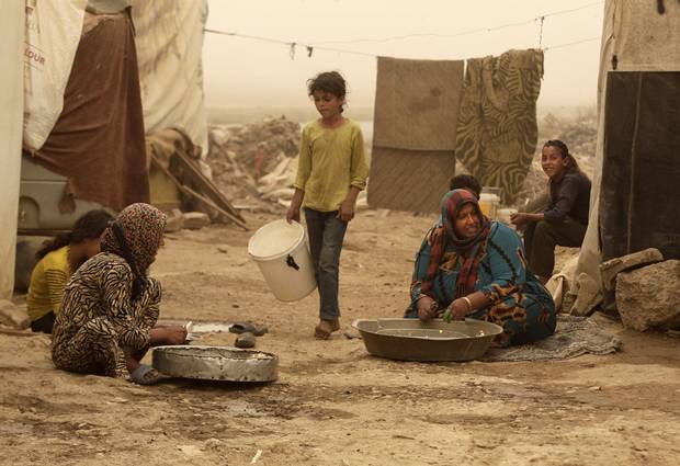 Syrian refugees peel garlic outside their tents during a sandstorm, in a refugee camp in the town of Bar Elias, in Lebanon's Bekaa Valley, Tuesday, Sept. 8, 2015. Many residents of the camp peel garlic for restaurants, getting 30 cents in return for every kilogram of garlic they peel. The unseasonal sandstorm hit Lebanon and Syria, reducing visibility and sending dozens to hospitals with breathing difficulties because of the fine dust.
