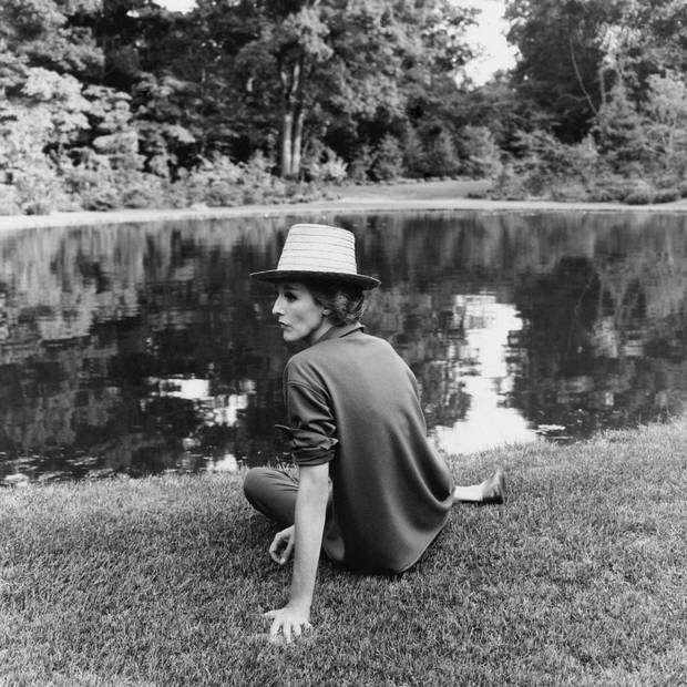 Barbara Paley, in casual attire, lounges beside the pond in her garden on Long Island.