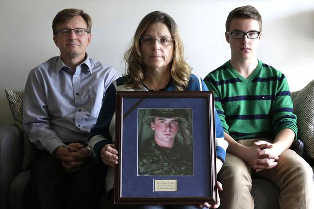 Anita Cenerini holds a portrait of her son, Private Thomas Welch, at her Winnipeg home in October 2016, with Pte. Welch's stepfather, Grant Palmer, left, and brother, Jacob Cenerini-Palmer, right. In 2004, Pte. Welch, suffering from post-traumatic stress disorder, died by suicide three months after returning from Afghanistan.
