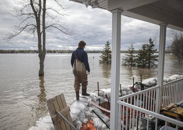 Patrice Pepin walks along a barrier of sandbags holding back the Ottawa River's waters at the home of his brother Christian Pepin and wife Marie-Pierre Chalifoux on Fournier street in the municipality of Saint-Andre-d'Argenteuil, on May 9, 2017.