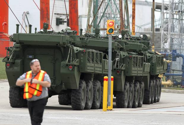 A security guard walks in front of three LAVs parked on the lot of the General Dynamics factory in London, Ont.