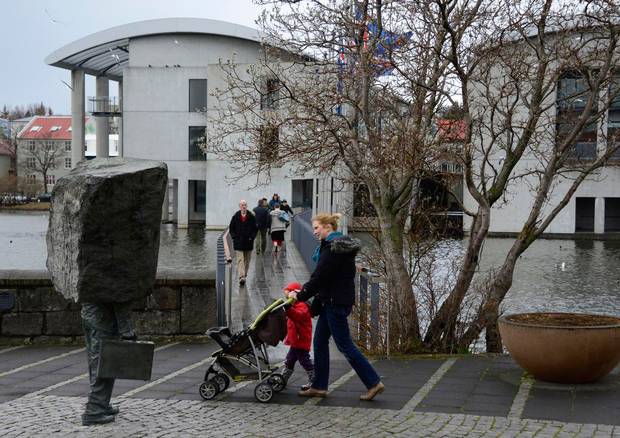 A woman pushes a stroller as she passes the City Hall polling station in Reykjavík, Iceland.