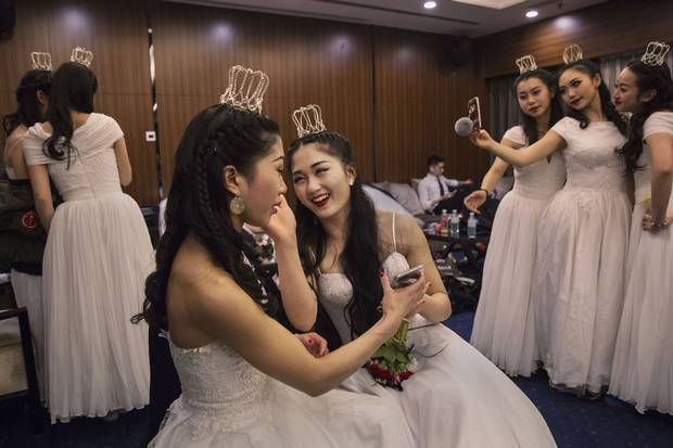 Debutantes from a local academy laugh as they get ready to take part in the Vienna Ball at Beijing’s Kempinski Hotel on March 19, 2016. Social mobility and economic status are largely shaped by hukou.