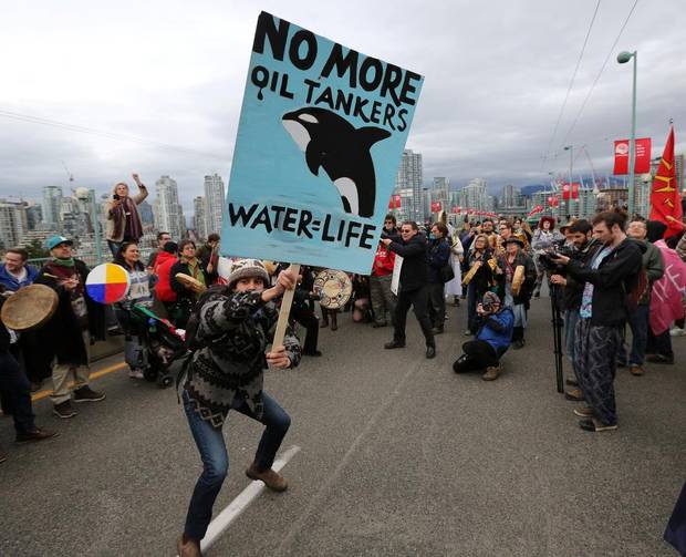 A protester dances with a sign during a march against the proposed expansion of Kinder Morgan's Trans Mountain Pipeline, on the Cambie Street bridge in Vancouver, B.C., on November 19, 2016.