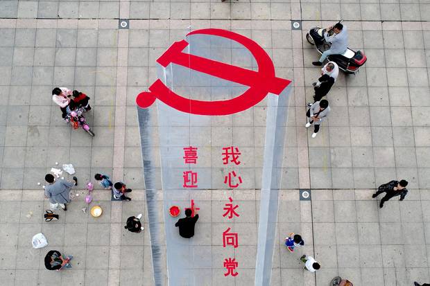 Xiayi, Henan province: A man working on a 3-D street painting of the emblem of Chinese Communist Party.