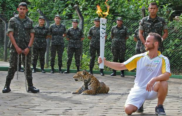 An athlete holds the Olympic torch by a jaguar, a symbol of Amazonia, during a ceremony in Manaus, northern Brazil, on Monday.