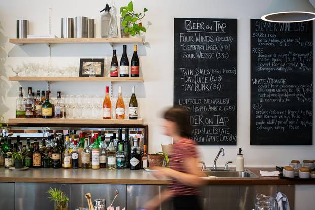 A server walks behind the bar at Bows & Arrows in Vancouver on Sept. 6, 2017. 