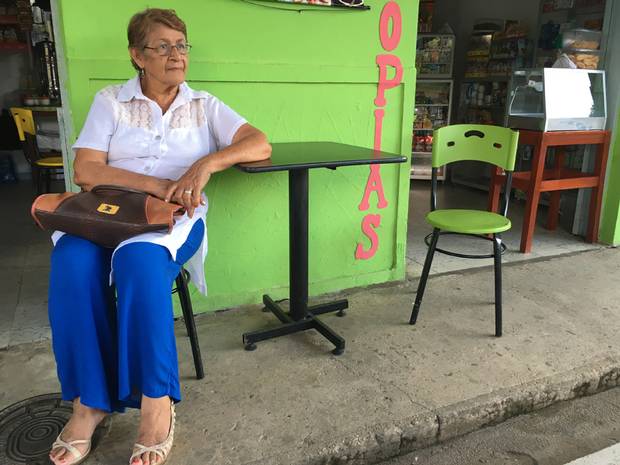 Maria Luisa Celis sits outside the building that the FARC attacked during a town council meeting she was attending in 2005. The building is now an ice cream and photocopy shop.