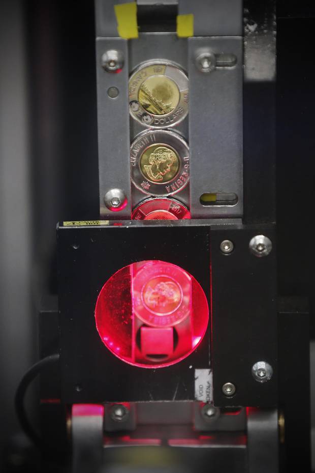 Two dollar coins are tested before being painted with glow in the dark paint at the Royal Canadian Mint in Winnipeg Tuesday, April 4, 2017. 