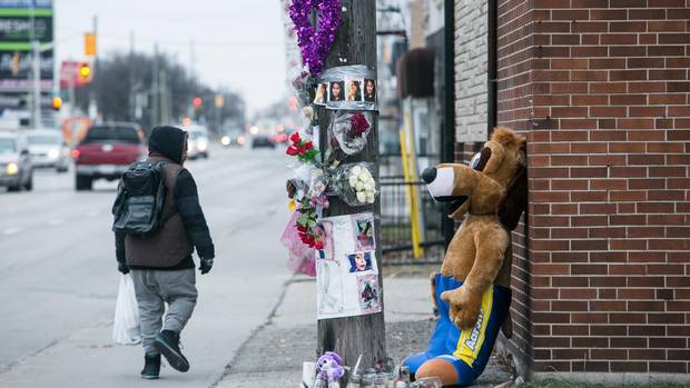 A passerby glances at a memorial for Holly Hamilton at an intersection not far from where her body was found in the trunk of her car in Hamilton.