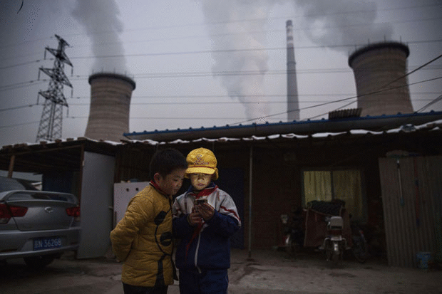 What a difference three years makes. In November, 2015, Chinese boys are shown checking smartphones next to a coal-fired power plant on the outskirts of Beijing, a year after Chinese premier Li Keqiang declared 