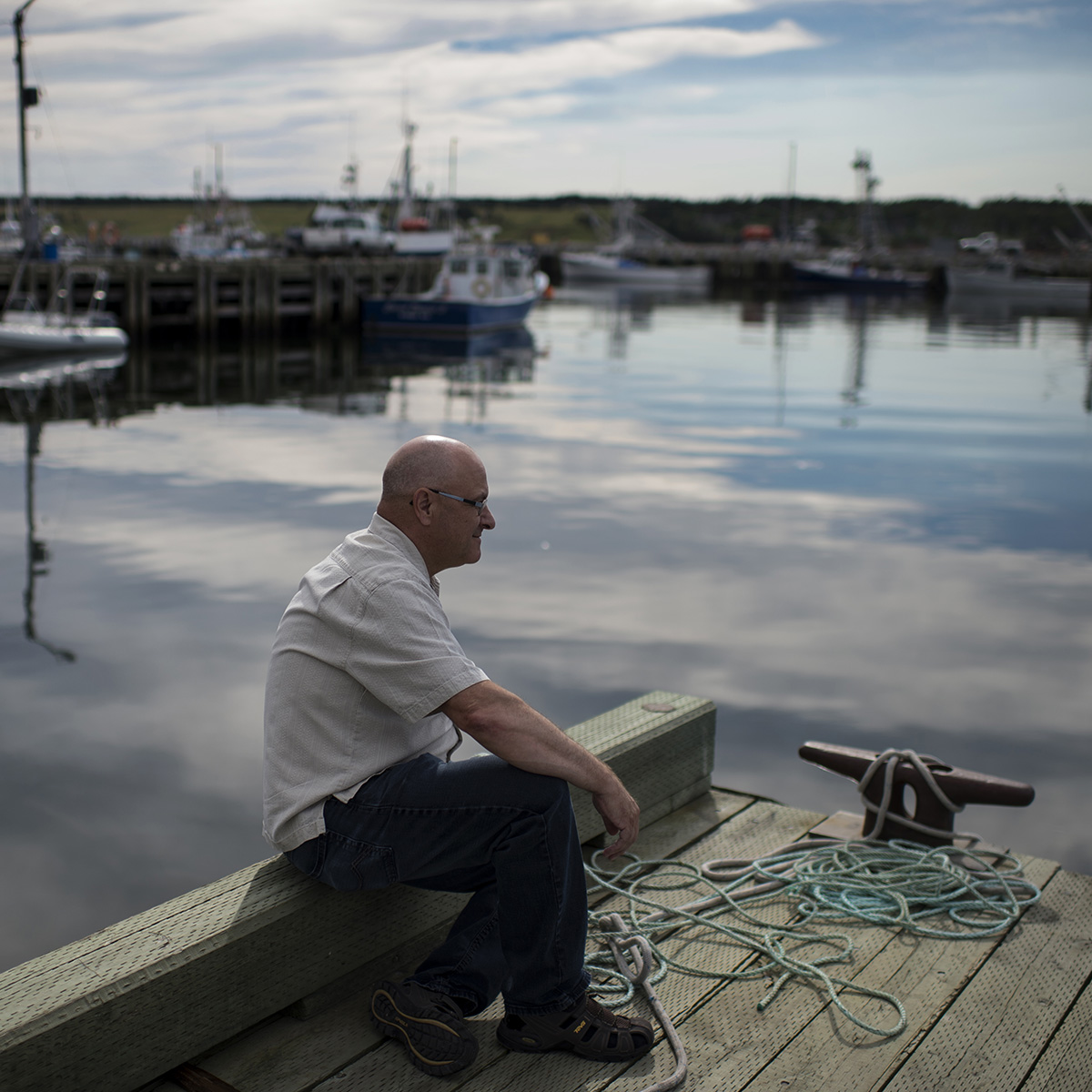 Retired fisherman Leonard LeBlanc sits at the wharf in the Cheticamp Harbour in Cheticamp, N.S., not far from where an accident aboard his fishing boat took the life of his five-year-old son.