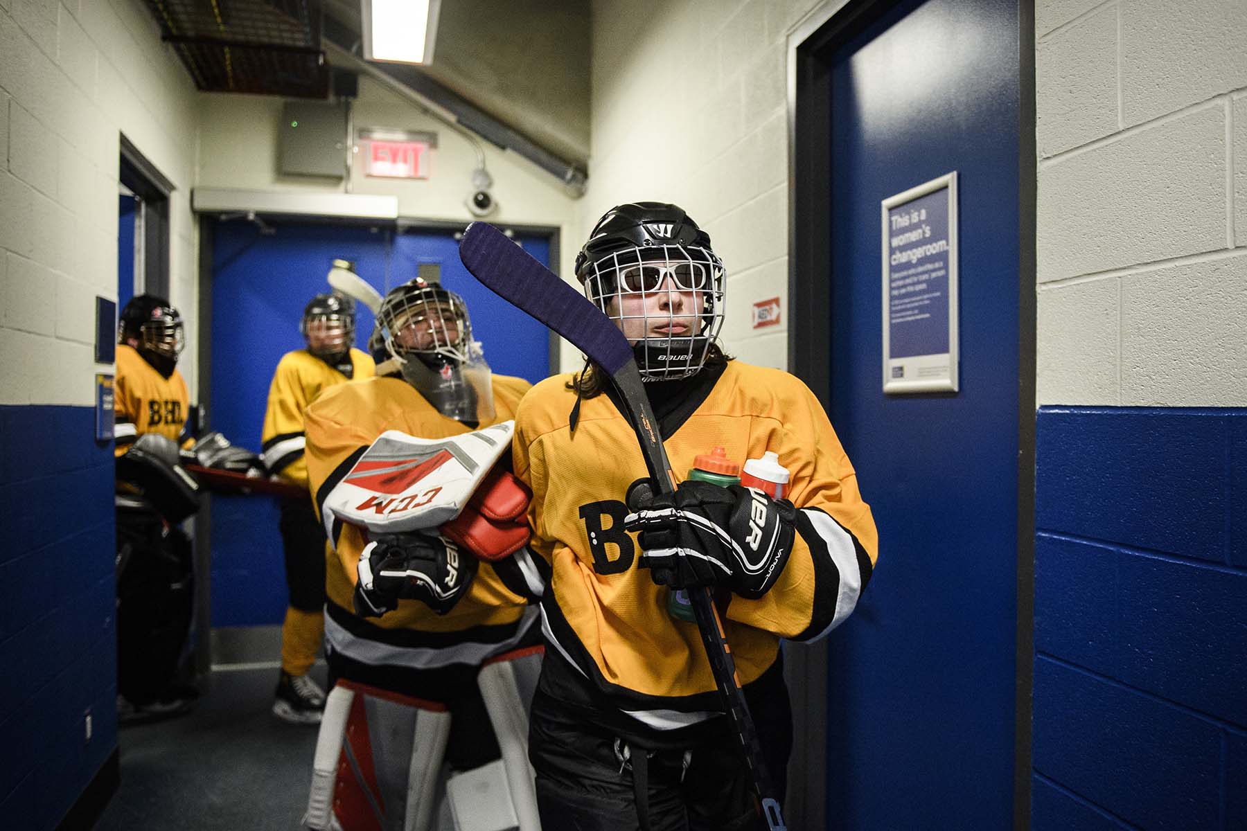 Amanda Provan leads goalie Joey Cabral and other players through a doorway and a blue-walled hallway at the arena during the Carnegie Cup elite Blind Hockey Series in Toronto.