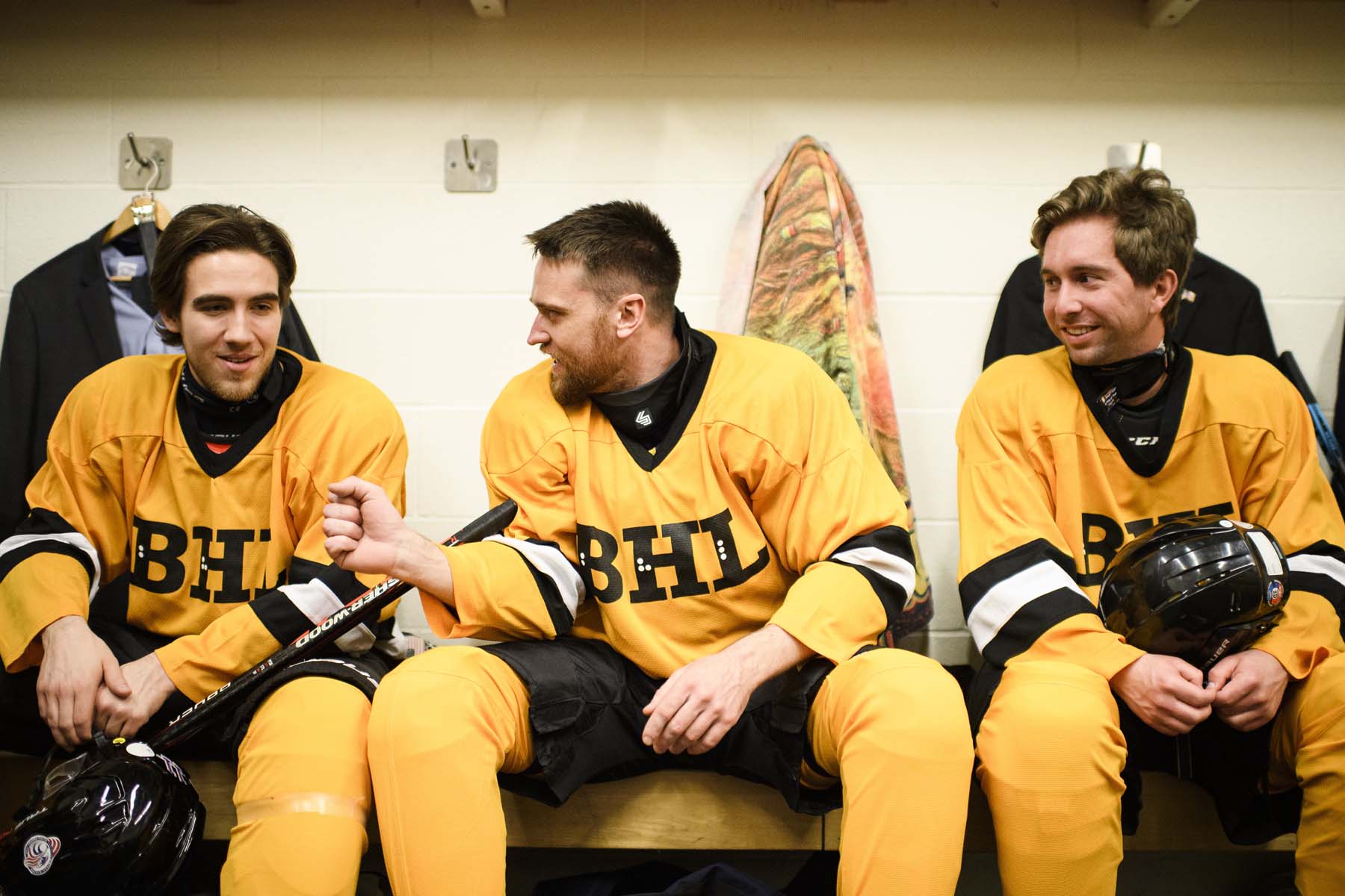 Dan Schramm and teammates, wearing yellow team sweaters, sit and chat on a bench in a dressing room during the Carnegie Cup elite Blind Hockey Series in Toronto.