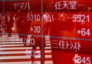 FILE PHOTO: Passersby are reflected on an electric stock quotation board outside a brokerage in Tokyo, Japan April 18, 2023.  REUTERS/Issei Kato/File Photo