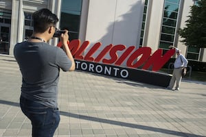 A man takes a photograph of the sign next to the entrance of Collision 2022 at Enercare Centre, Toronto June 22, 2022. The event is the largest international in-person gathering in Toronto in more than two years.
