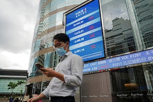FILE PHOTO: People walk past a screen displaying the Hang Seng stock index outside Hong Kong Exchanges, in Hong Kong, China July 19, 2022. REUTERS/Lam Yik