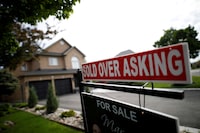 FILE PHOTO: A real estate sign that reads "For Sale" and "Sold Above Asking" stands in front of housing in Vaughan, a suburb in Toronto, Canada, May 24, 2017.    REUTERS/Mark Blinch/File Photo