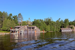 On July 17, 2026 one of Canada’s most extraordinary private estates became the backdrop for one of the country’s most influential gatherings. Prime Minister Mark Carney was in Muskoka for the invitation-only Dock (un)Conference, hosted at Ferndale, the Lake Rosseau estate of Peter Gilgan, founder of Mattamy Homes. Bringing together leaders in business, technology and government, the conference is designed to encourage open discussions about Canada’s future in a private setting.
Cruising by two of the five boathouses on the Ferndale property on Lake Rosseau. At one time this magnificent property was called Ferndale House (a grand resort) and later it was sold to a Christian organization called the Canadian Keswick Conference Centre. It burned down in 1946. The property now supports five boathouses along with a massive cottage, guesthouse, sandy beach, sports courts and a helicopter pad. The property is owned by a self made Canadian Billionaire who has amassed great success in the home building business. July 24, 2026
On July 17, 2026 one of Canada’s most extraordinary private estates became the backdrop for one of the country’s most influential gatherings. Prime Minister Mark Carney was in Muskoka for the invitation-only Dock (un)Conference, hosted at Ferndale, the Lake Rosseau estate of Peter Gilgan, founder of Mattamy Homes. Bringing together leaders in business, technology and government, the conference is designed to encourage open discussions about Canada’s future in a private setting.
Cruising by two of the five boathouses on the Ferndale property on Lake Rosseau. At one time this magnificent property was called Ferndale House (a grand resort) and later it was sold to a Christian organization called the Canadian Keswick Conference Centre. It burned down in 1946. The property now supports five boathouses along with a massive cottage, guesthouse, sandy beach, sports courts and a helicopter pad. The property is owned by a self made Canadian Billiona