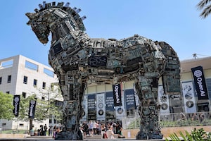 An art installation of a Trojan Horse comprised of e-waste appears on the Tel Aviv University campus while banners for OpenAI adorn a nearby building in 2023. A group of researchers left OpenAI and founded Anthropic in 2021 over concerns about the company’s resistance to guardrails to help regulate its AGI ambitions.