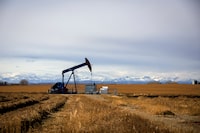 A Tourmaline pump jack in a farmers field with the Rocky Mountains for a backdrop just north of Calgary in October of 2019.