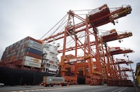 A transport truck carries a cargo container to be loaded at the DP World Centerm terminal at port in Vancouver on Sunday, Aug. 3, 2025. THE CANADIAN PRESS/Darryl Dyck